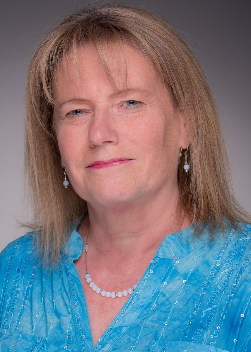 Dean Tammy O'Brien smile at the camera wearing a blue dress shirt.