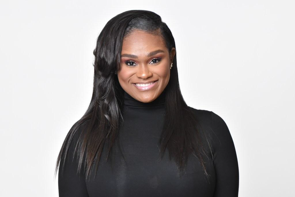 Ms. Nicole Crawley, an African American female with long black hair, smiles at the camera wearing a black turtle-neck sweater pictured against a white background.
