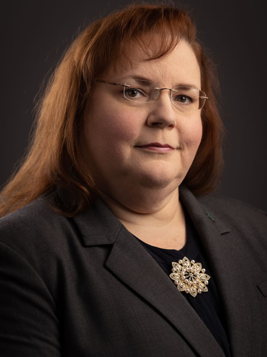 Mrs. Cheryl Ciucevich, a Caucasian female with shoulder length red hair, smiles wearing a black and white polka dot dress.